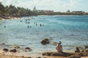 People enjoying the turquoise waters and sandy shores of San Juan's picturesque beach under a clear summer sky.