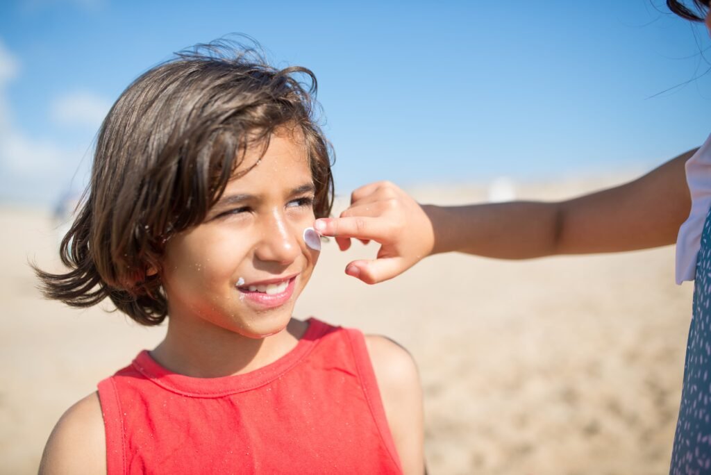 pexels-photo-8926001-8926001 Child with sunscreen on face at sunny beach, enjoying summer day outdoors in Portugal.